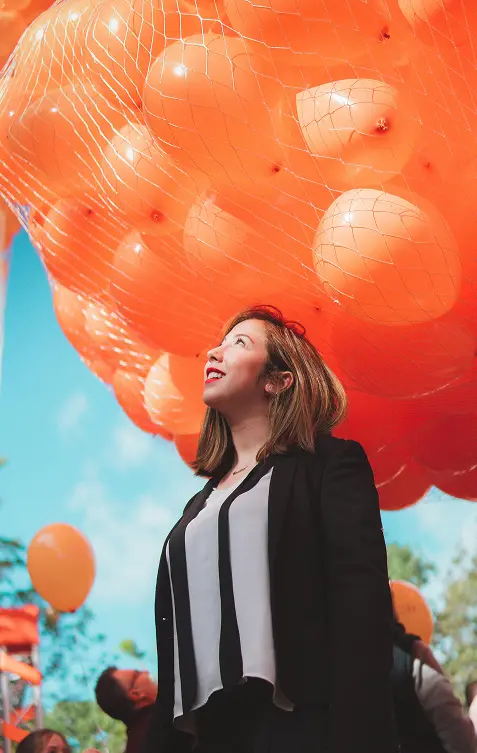 Woman with net full of orange balloons above her
